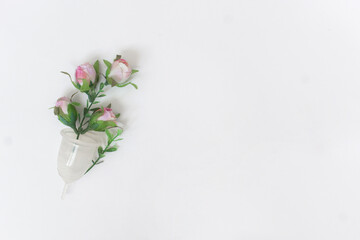 female personal hygiene products isolated on a white background menstrual cup and a pink flowers as a choice eco-friendly zero waste reusable product for a period of time.