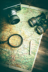 Magnifying glass, camera and binoculars on the old map.