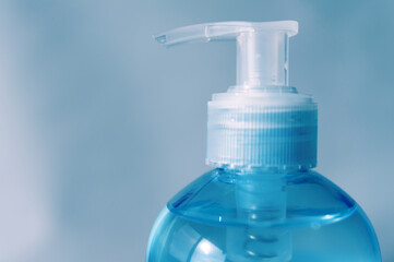 Close-up of pump bottle head. Alcohol gel or hand sanitizer. Protection against Coronavirus (COVID-19). Isolated on blue background. Copy space.