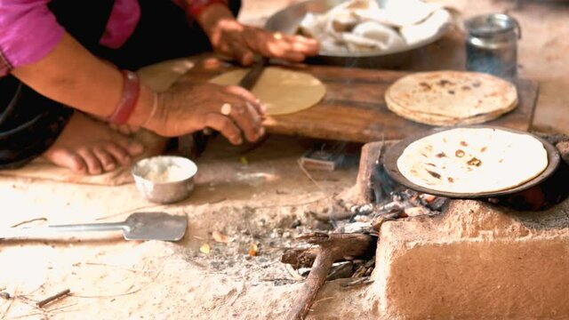 Woman cocking roti,Indian village woman cooking food with traditional way of baking chapati on wood fire stove (chulha), selective focus ,Whole Wheat Flat Bread, Chapathi, Wheaten Flat Bread, Chapatti