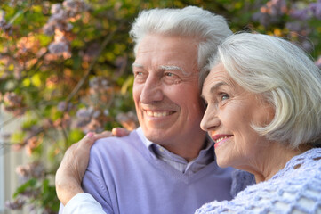Portrait of beautiful senior couple hugging in the park by lilacs