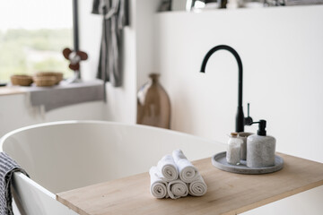 Towels on tub with modern black water tap at blurred background