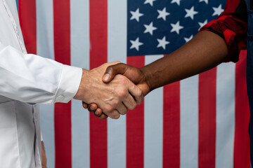 Contemporary clinician in whitecoat and young African repairman shaking hands