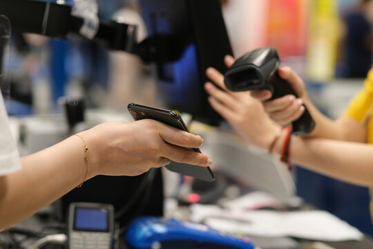 Close Up Hand Holding Phone To Scan To Pay At Checkout. Contactless Payment. Soft Focus