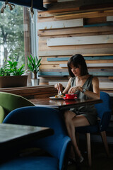 Mysterious woman in the corner of a cafe eating cake .