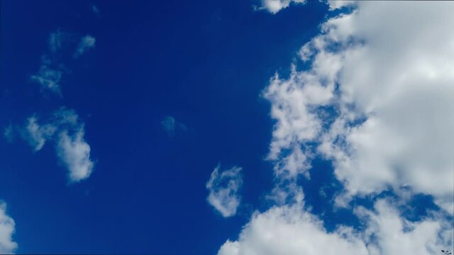 Timelapse Flight of white fluffy cumulus clouds on blue bright skies on a sunny day. 25 frames per second, 4K. A sunny fine day with clear skies and white clouds.