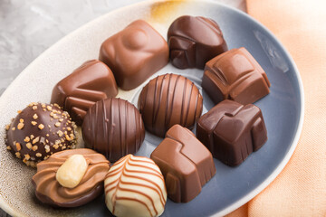 Different chocolate candies and a cup of coffee on a gray concrete background. side view, selective focus.