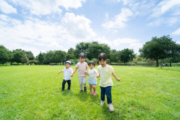 Obraz premium 青空の下、手を繋いで元気に歩く子供たち