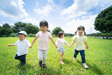 青空の下、手を繋いで元気に歩く子供たち