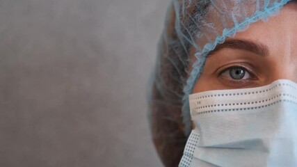 Nurse with protective medical cap and surgical face mask during the Coronavirus disease (COVID-19) outbreak epidemic. Close up portrait with a single use protection mask on the face.