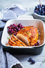Roasted turkey breast with grapes in black dish.