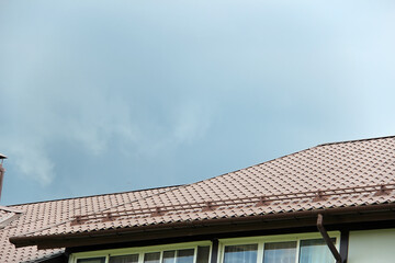 roof with new brown roofing tiles on residential property. banner on  roof for roofers. concept for...