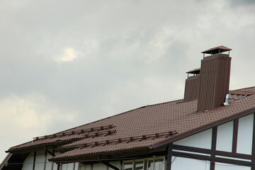 roof with new brown roofing tiles on residential property. banner on  roof for roofers. concept for...