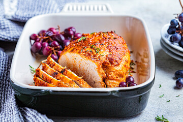Baked turkey breast with grapes in black dish, top view.