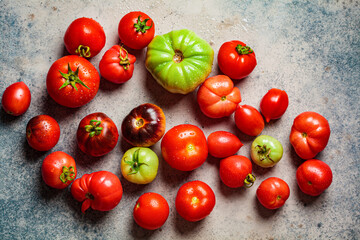 Whole multi-colored ripe tomatoes on dark blue background, top view.