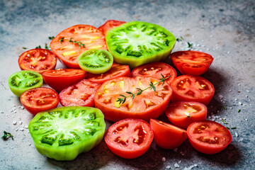 Sliced multi-colored ripe tomatoes on dark blue background, top view.