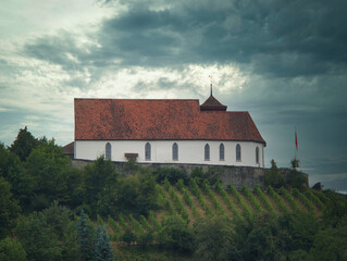 Modern Reformed Church Staufberg in Staufen under a dramatic sky and vineyard below the church, which is built on a hill.