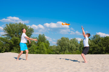 Boy and father are playing on the beach on a sunny warm summer day. Concept about sports and active games in summer. Healthy lifestyle.