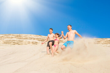 Happy family have fun running along the sand on the beach on a sunny summer day. Family vacation. Healthy lifestyle.