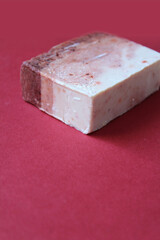 A single block of home made soap on a dark red background. Hand made soap with natural ingredients concept, high angle view. Copyspace below.