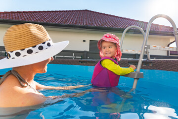 2-3 years old child with mother in swimming pool learn to swim. Summer at home concept.