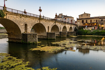 Vue au coucher du soleil sur le Pont Tibère et sa réflexion sur les eaux du fleuve Vidourle à Sommières (Occitanie, France)