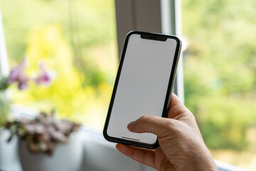 Woman hand holding the black smartphone with blank screen and modern frameless design Frau hält...