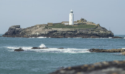 Fototapeta na wymiar A white lighthouse at sea in Cornwall, England.