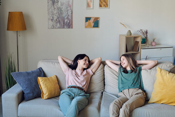 Obraz premium Cheerful and relaxed mother and daughter in casualwear chatting on couch