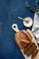 Country sourdough bread on a wooden light board on a dark background, top view, vertical background, copy space, flay lay, top-down food