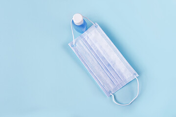 Hygienic set of bottle with antiseptic sanitizer gel and protective medical face mask. Hygiene products. Protection during the coronavirus epidemic. Copy space for text, flat lay