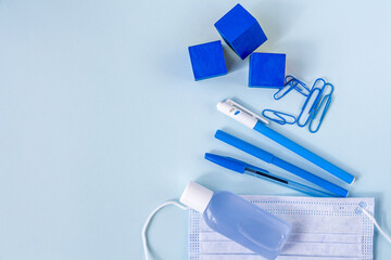 Education or back to school concept. Blue school supplies and medical face mask. New normal during...