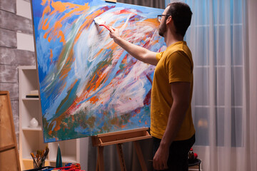 Man using oil paint on large canvas in art studio. Modern artwork paint on canvas, creative, contemporary and successful fine art artist drawing masterpiece