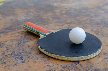 Close-up of a ping pong ball and racket on a tennis table.