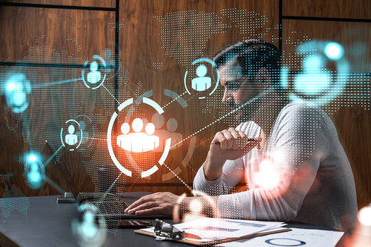 A serious caucasian manager in casual wears, using laptop to develop a new network. Double exposure. Social media hologram.