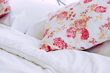Bright bedroom interior with flower pattern pillows on bed 