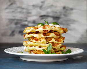 A stack of vegetable zucchini waffles with the addition of cheese on a light plate