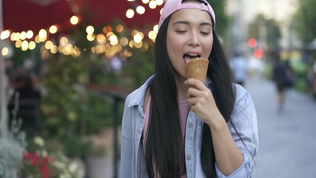 Young asian woman eating icecream at the street. Slowmotion.