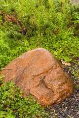 Element of landscape design, part of rockery - a large natural boulder, stone in the grass
