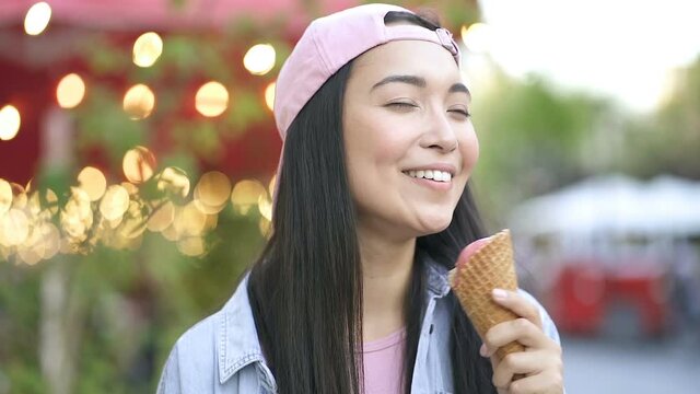 Close up portrait of asian woman licking icecream and smiling. Slowmotion.