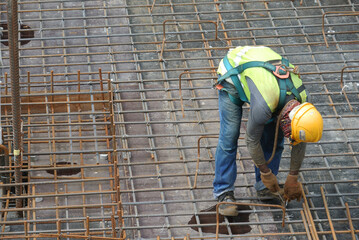 MALACCA, MALAYSIA -MAY 27, 2016: Construction workers fabricating steel reinforcement bar at the construction site in Malacca, Malaysia. The reinforcement bar was ties together using tiny wire.  