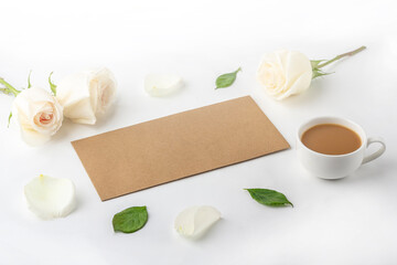 Flat lat flowers romantic composition. Morning coffee mug for breakfast, empty notebook with copy space for text or lettering and white roses. Female blogger workplace.