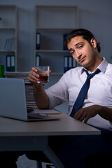 Alcohol addicted businessman working late in the office