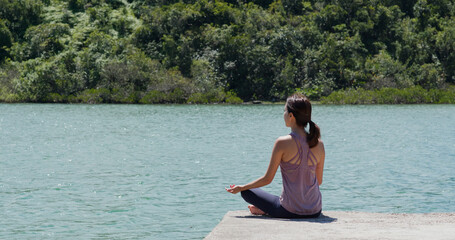 Fototapeta na wymiar Woman do yoga and sit beside the sea