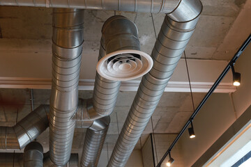 Ventilation pipes in silver insulation material hanging from the ceiling inside the new building.