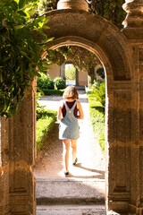 Attractive young female visiting an old monastery in Spain with a face mask and carrying a reflex camera with her