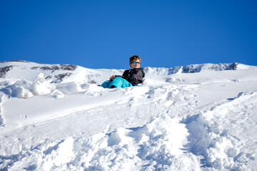 Fototapeta na wymiar Young Boy Sitting On The Snow Mountain. Winter time