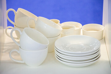 A set of white ceramic dishes stands on the shelf