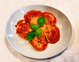 tasty first course with tomato, homemade ravioli with basil, parm  cheese, ricotta cheese, organic ingredients, typical Italian culinary specialties for lunch or dinner. Traditional and genuine dish