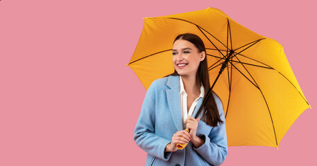Portrait of cute girl holding umbrella at pink studio